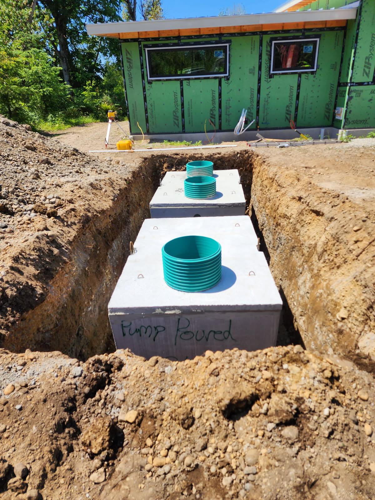 Concrete septic tank installation with risers at new construction site